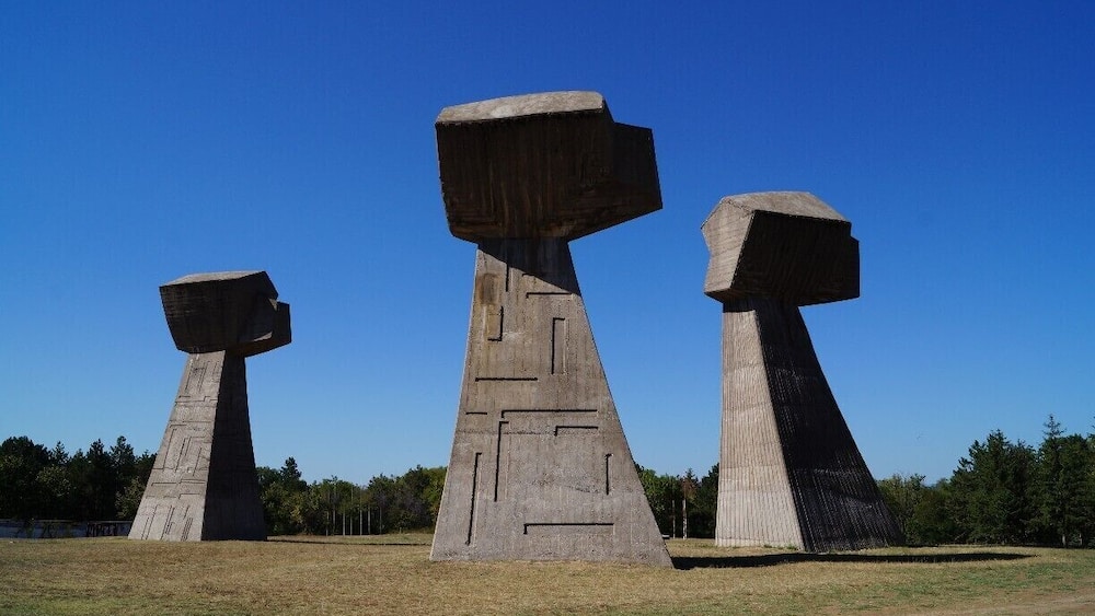 Trois grandes sculptures en béton, installées en plein champ.