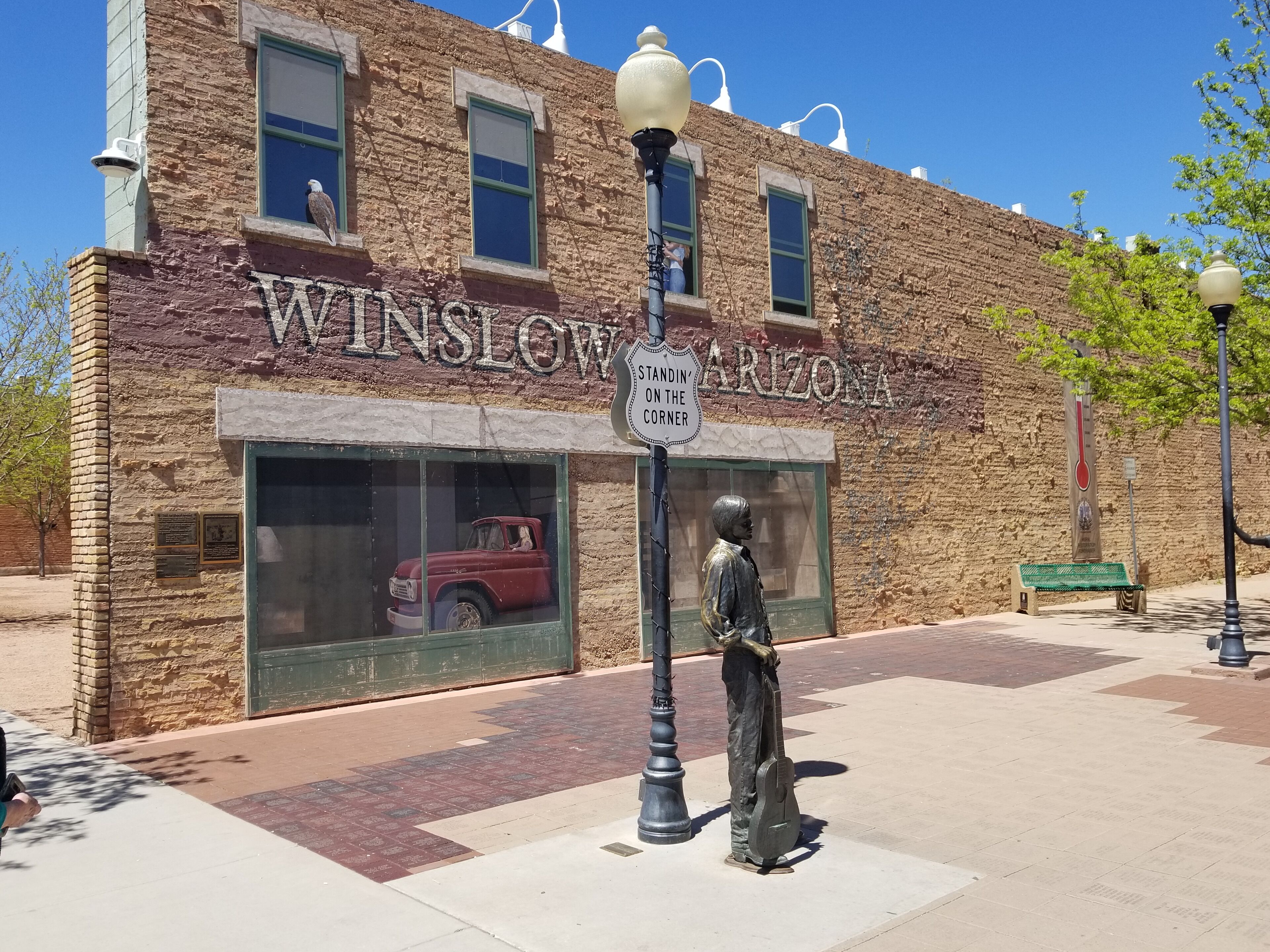 A building with a large window displaying a vintage car and a statue of a man playing a guitar.