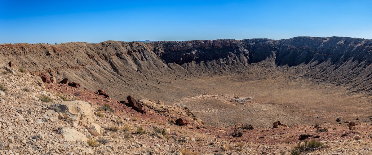 A vast, rugged canyon with steep, rocky walls and sparse vegetation.