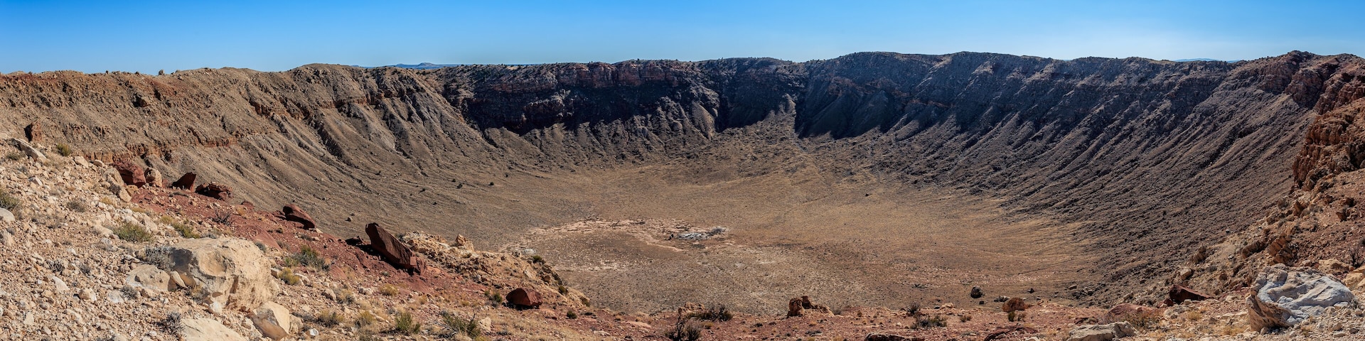 A vast, rugged canyon with steep, rocky walls and sparse vegetation.
