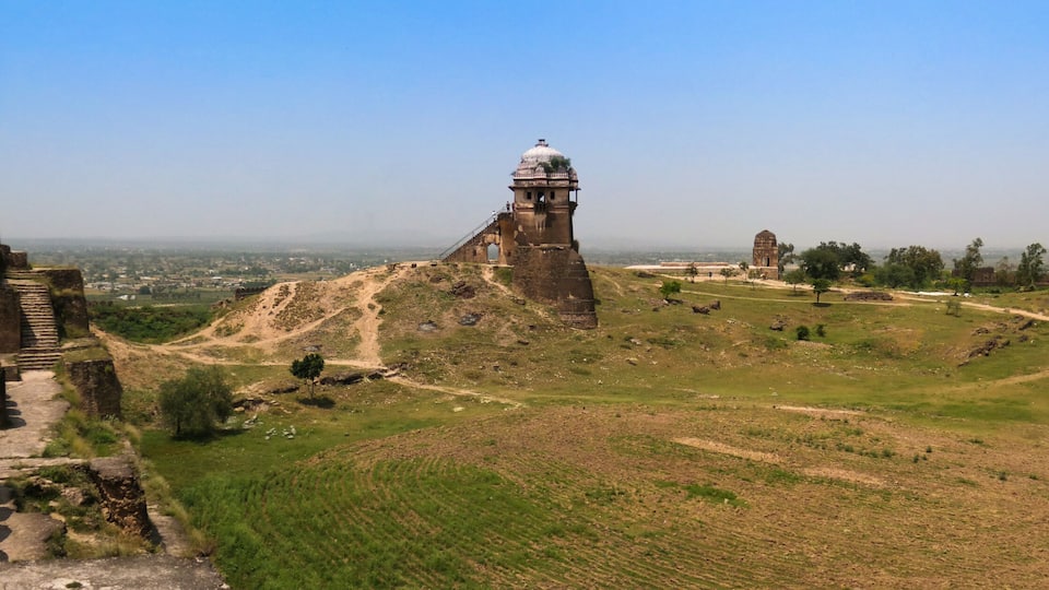 Ancient ruins with a large tower and a fortification wall.