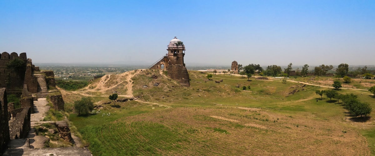 Ancient ruins with a large tower and a fortification wall.