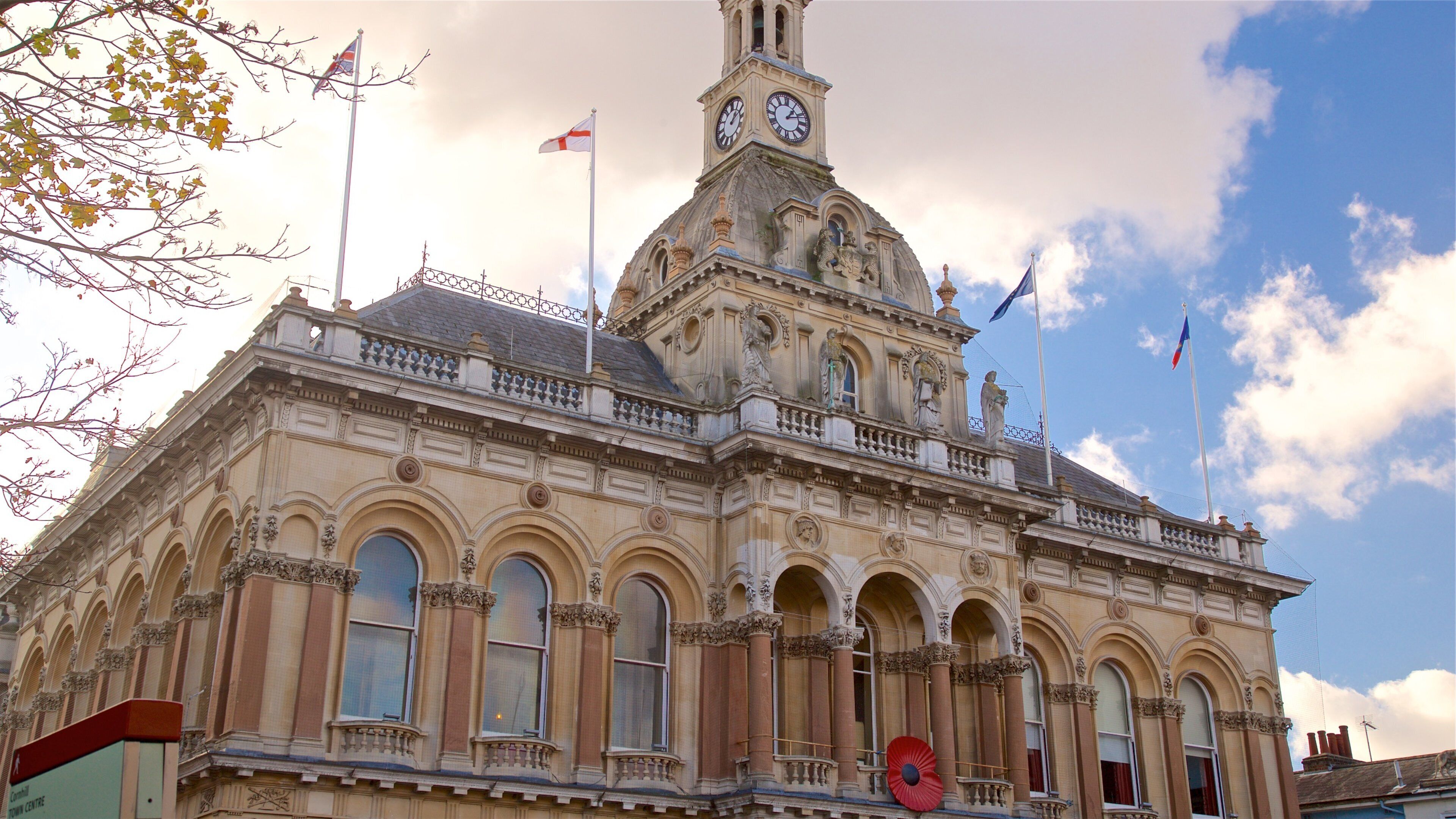 A historic building with ornate architecture, a clock tower, and multiple flags.