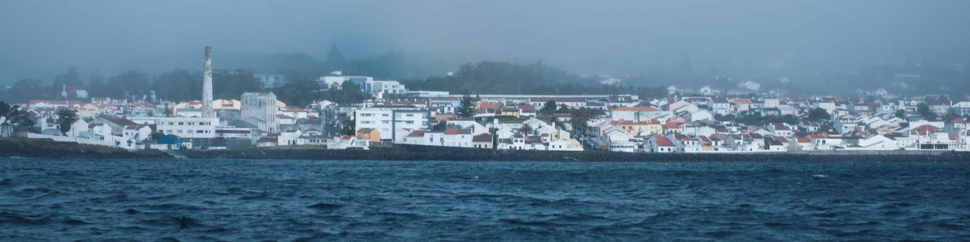 A coastal town with a prominent lighthouse and white buildings along the shoreline.