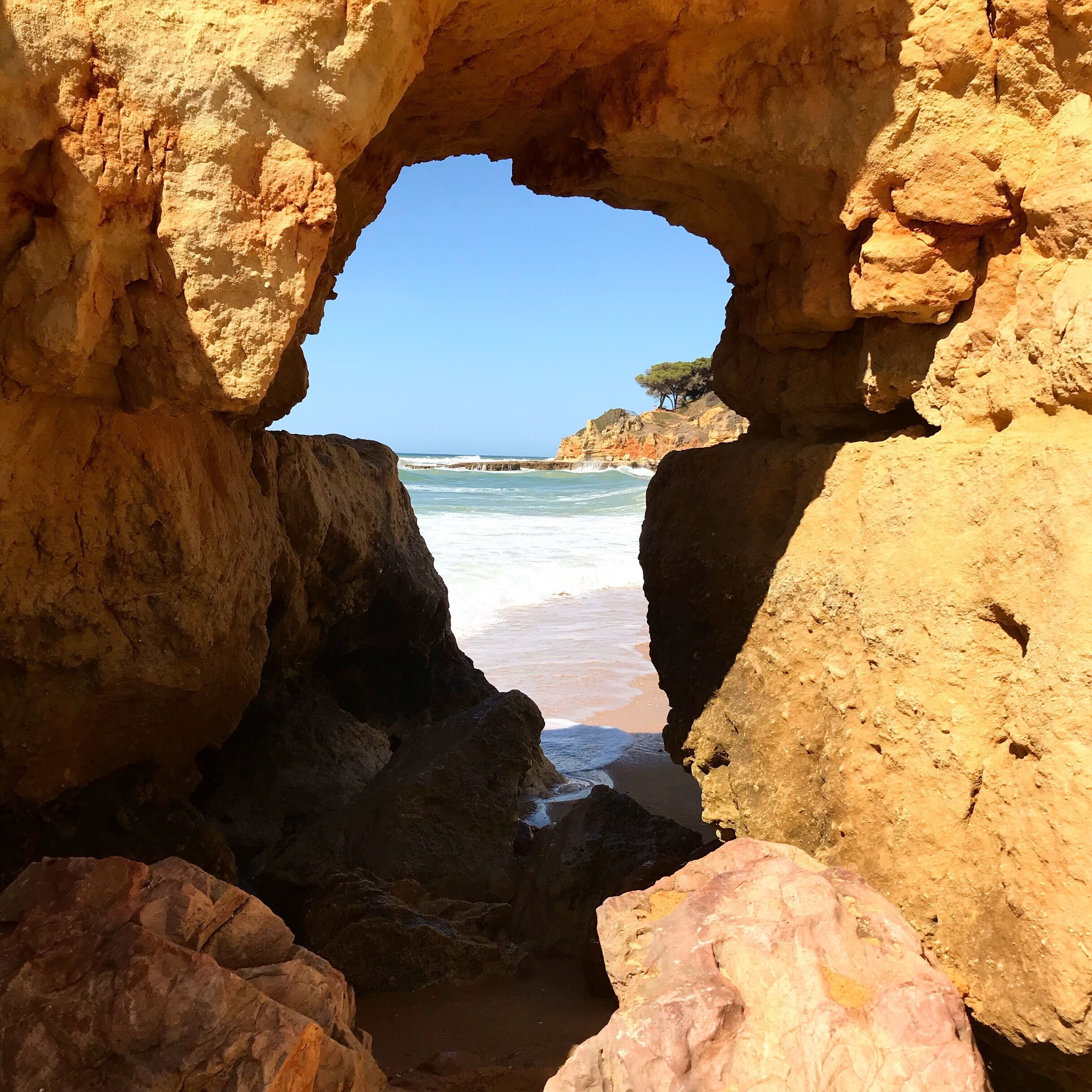 Formação natural de arco de pedra com uma praia e oceano ao fundo.