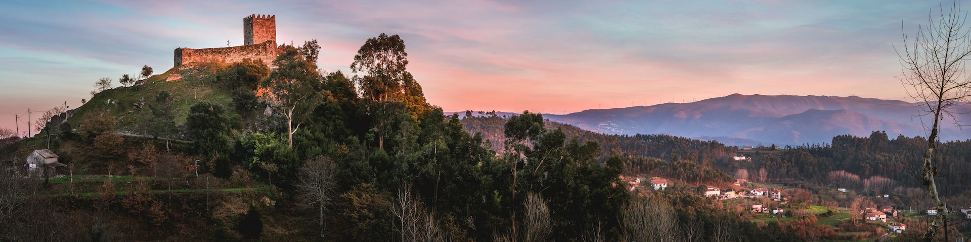 A historic castle on a hill with a village in the valley below.