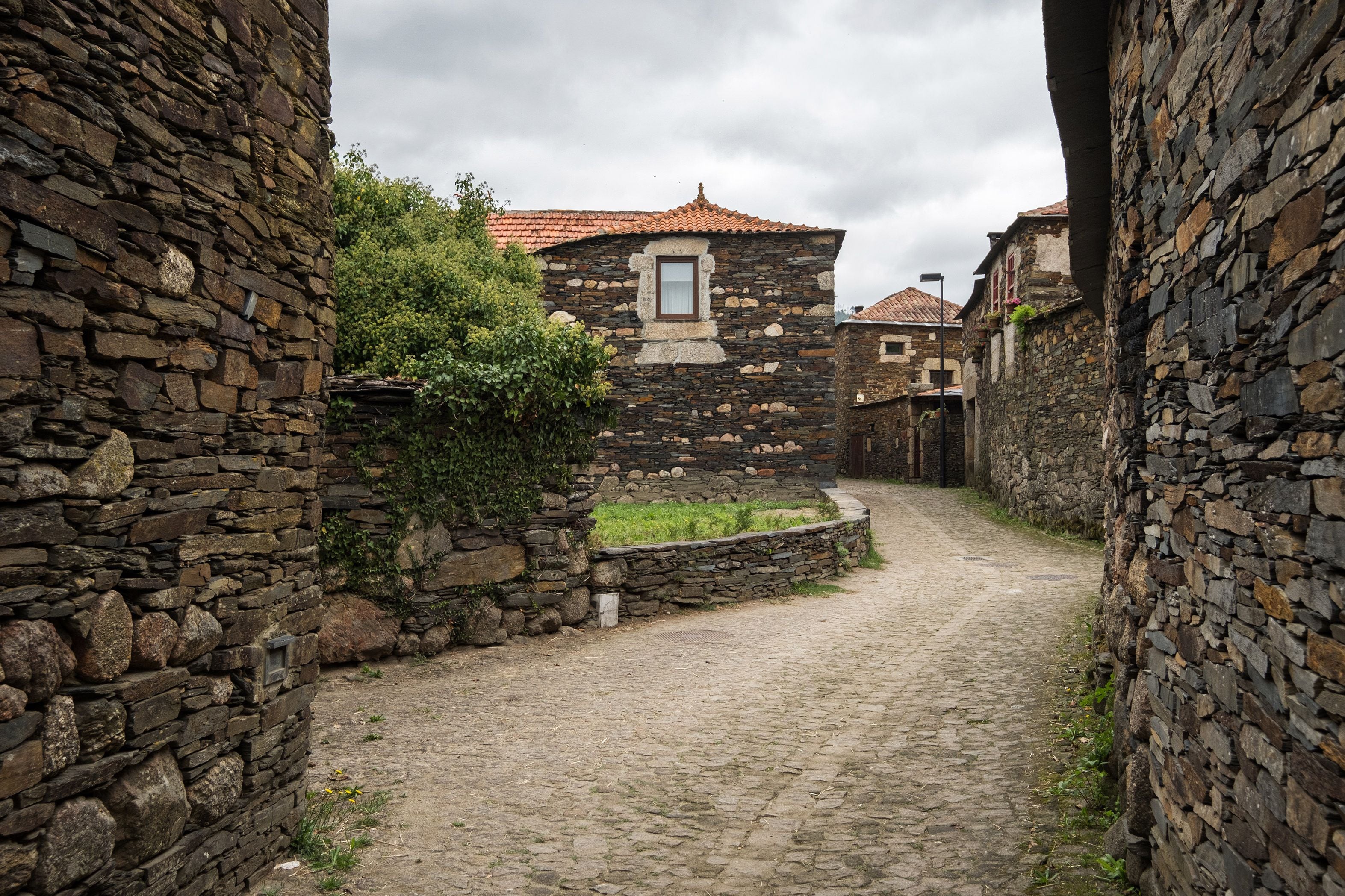 Un estrecho callejón adoquinado flanqueado por edificios de piedra con techo de tejas tradicionales.