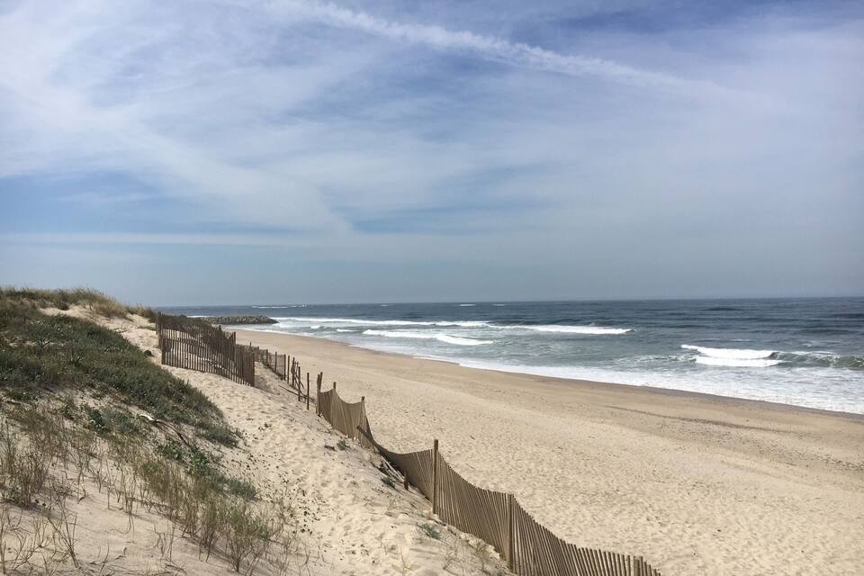 Une plage de sable avec une clôture en bois et des dunes.