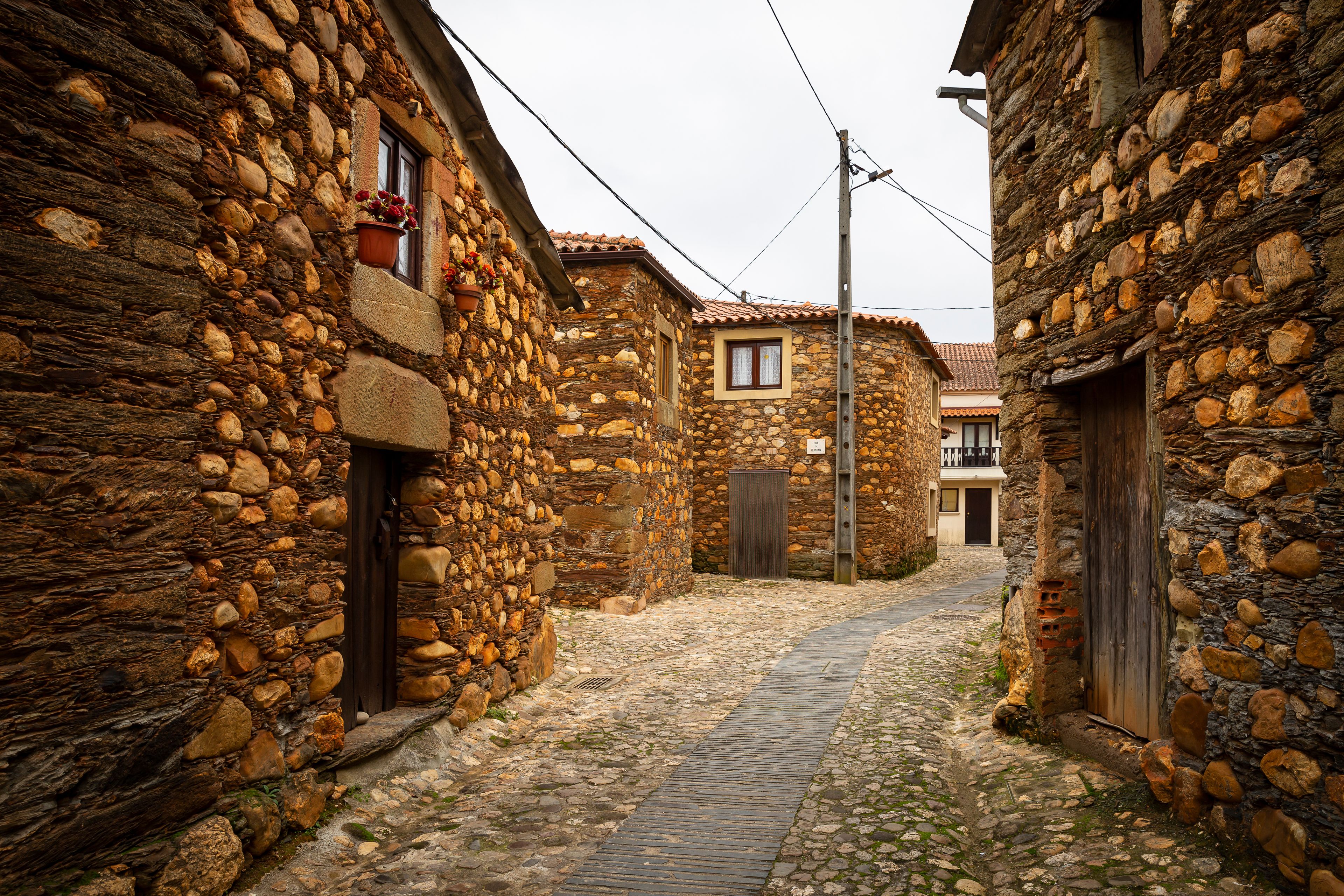 Uma rua de paralelepípedos estreita, ladeada por edifícios de pedra com telhados de cerâmica.