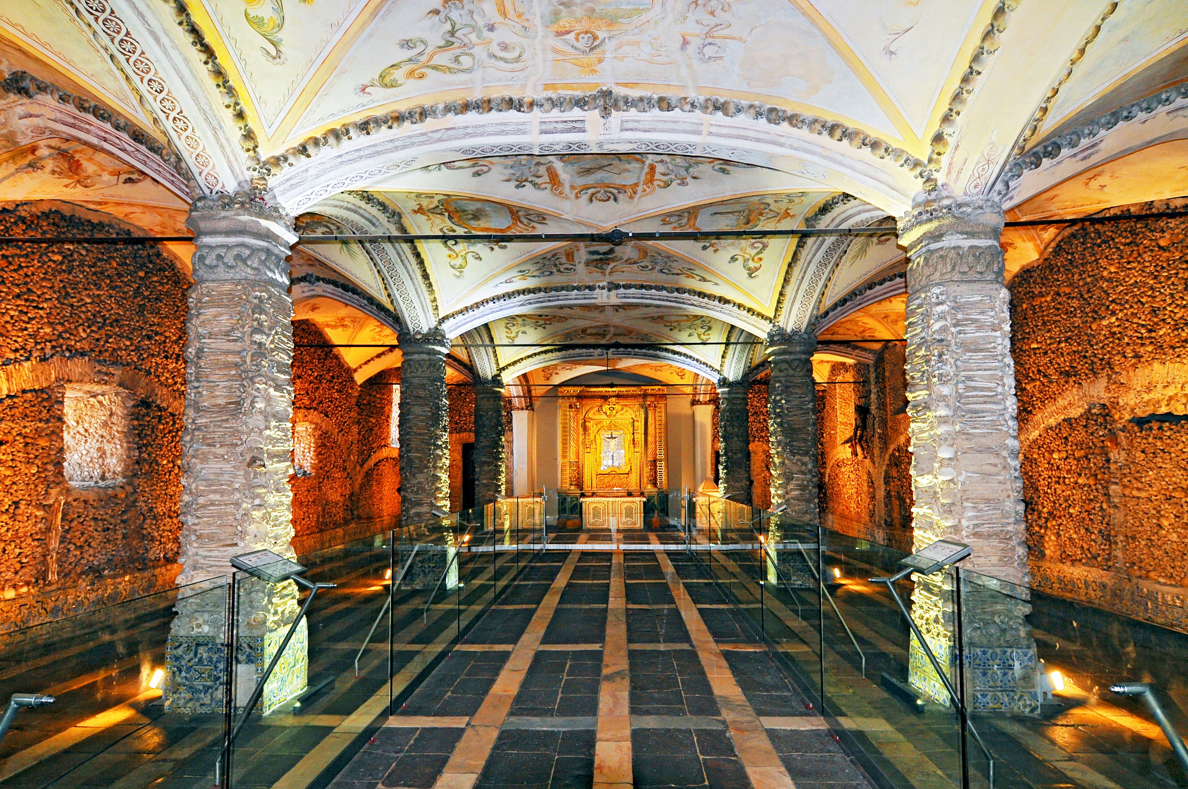 An ornate interior with a central altar, stone columns, and a patterned floor.