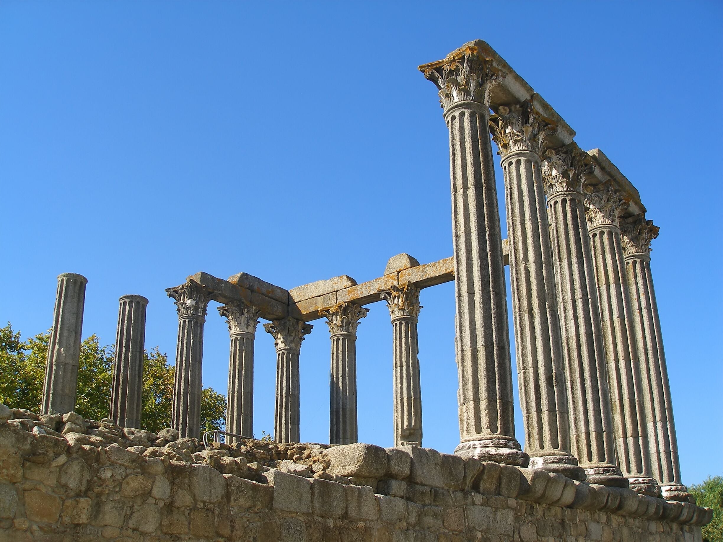 Ancient stone columns with intricate carvings, set against a clear blue sky.