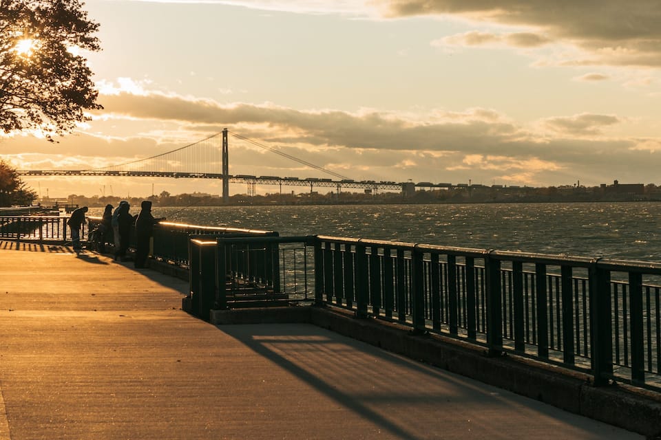 A riverside walkway with a bridge in the background.