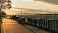 A riverside walkway with a bridge in the background.
