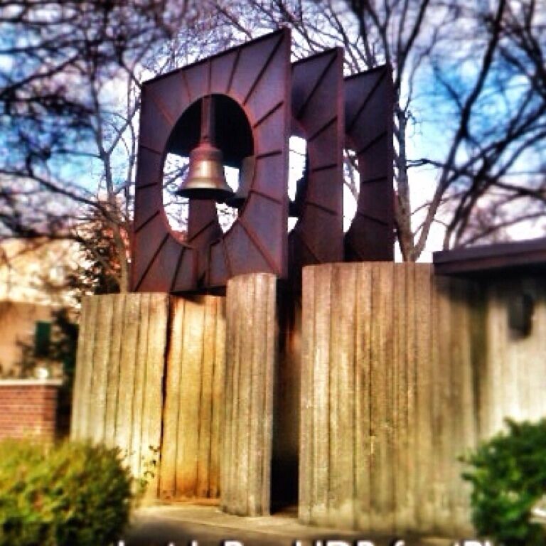 A cool bell installation at a church in Sturgis, MI. It is donated and dedicated in the name if a parishioner. The opening below it is a walkway which opens up to a small courtyard garden/park with benches, well suited for quiet contemplation. 
#bell #monument #church #park #square #courtyard