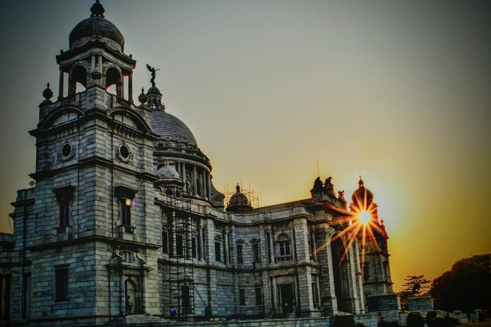 A historic cathedral with multiple domes and a prominent bell tower, bathed in the warm glow of the setting sun.