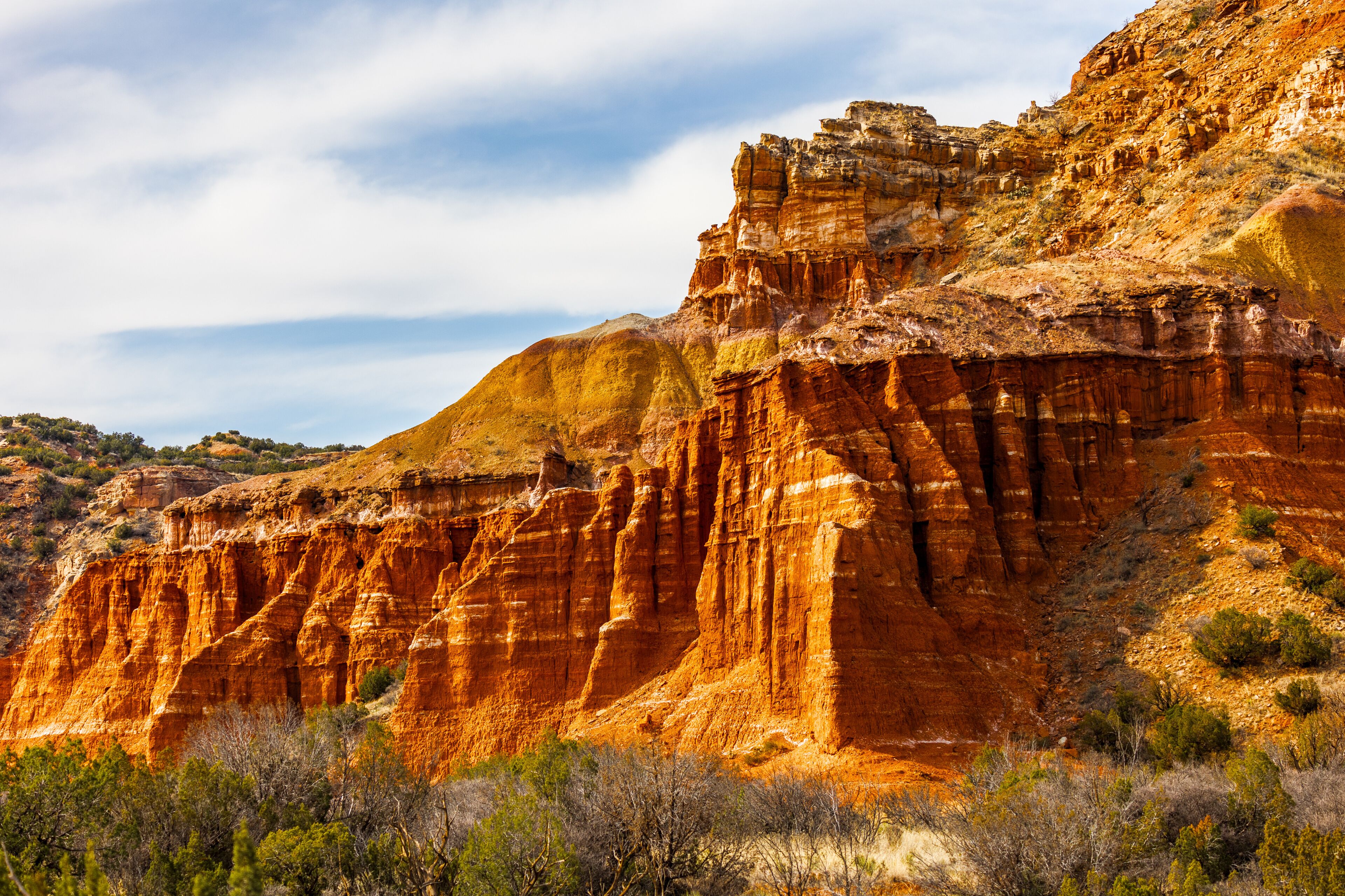A rugged canyon with layered rock formations and sparse vegetation.