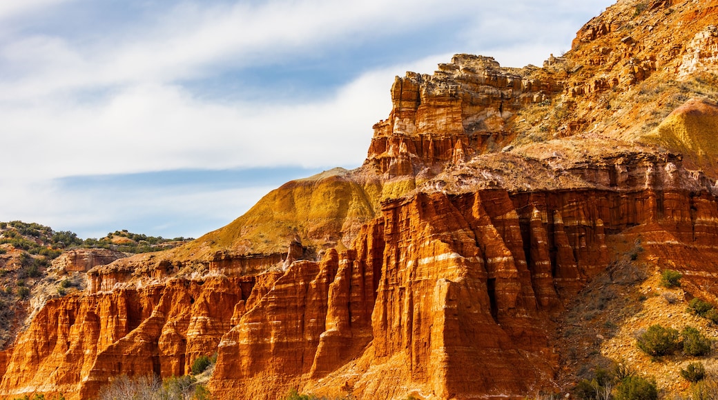 A rugged canyon with layered rock formations and sparse vegetation.
