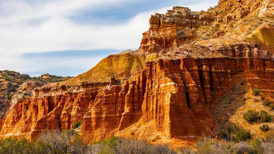 A rugged canyon with layered rock formations and sparse vegetation.