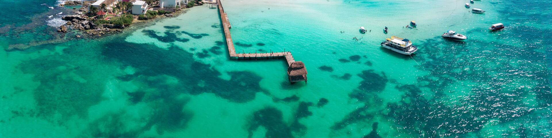A coastal resort with clear turquoise waters, a pier, and boats.