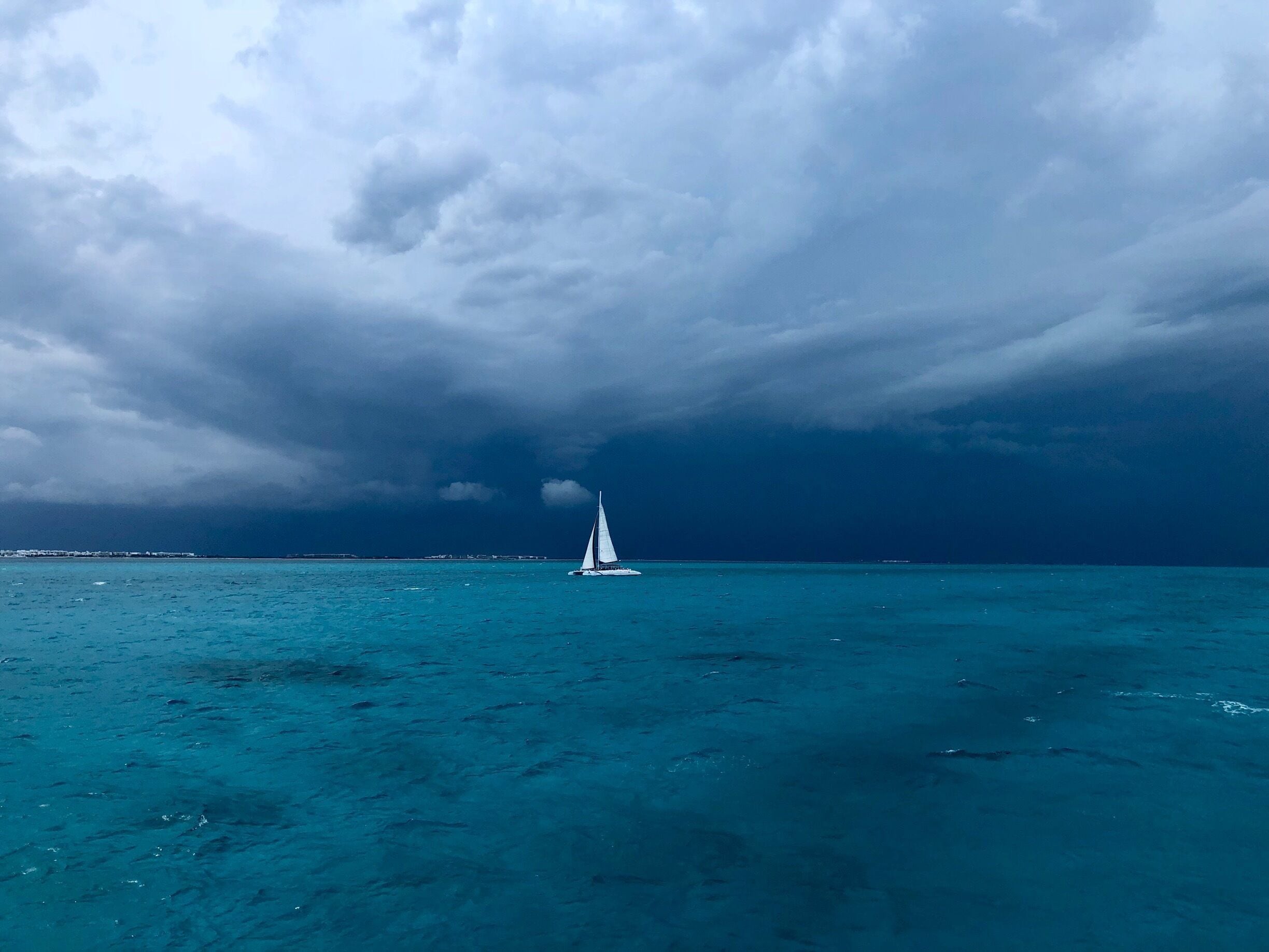 Un velero en aguas turquesas bajo un cielo nublado.
