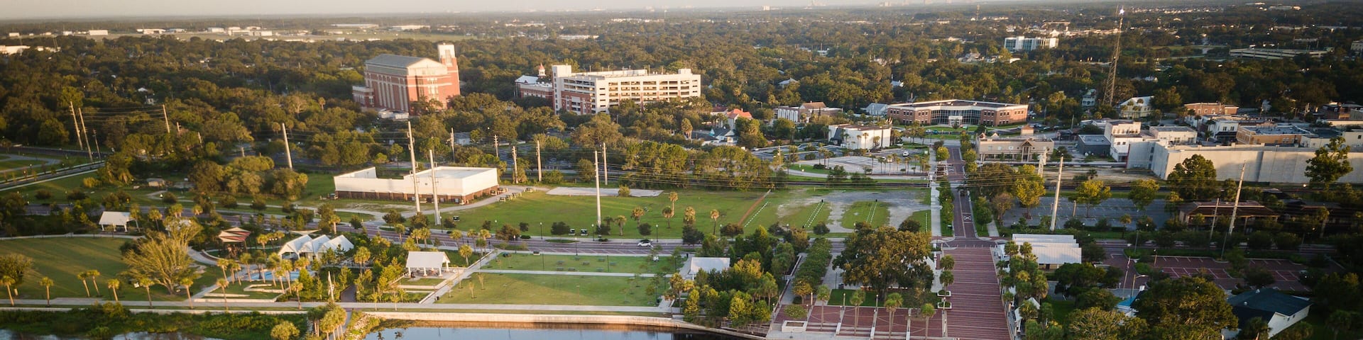 An aerial view of a lake with a dock, surrounded by buildings and greenery.