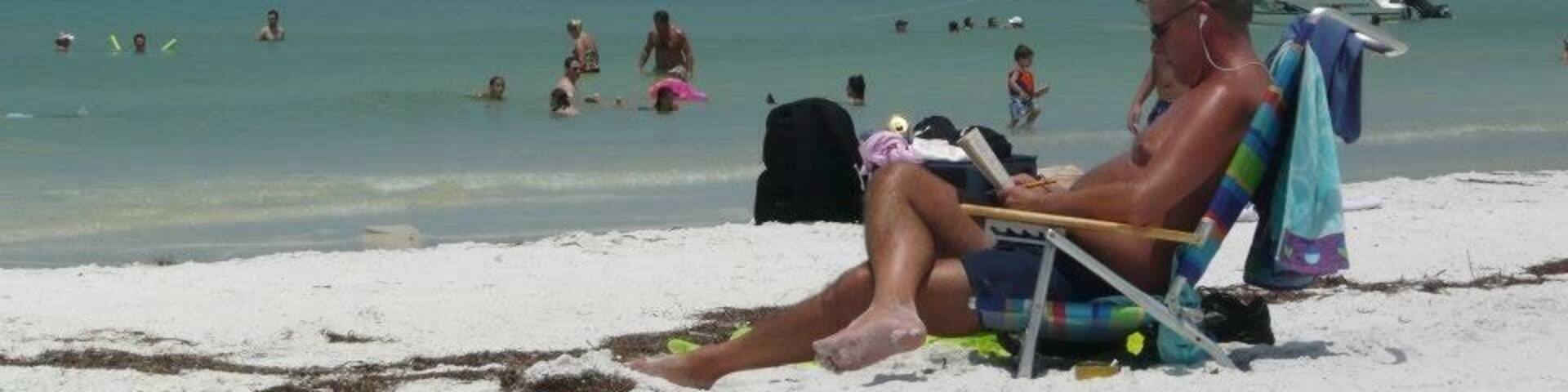 A beach with people swimming and sunbathing.