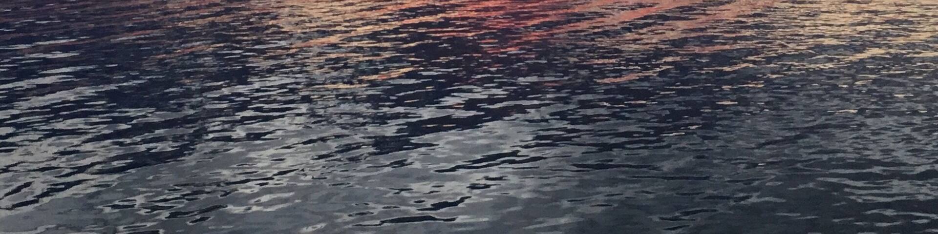 A sunset over a calm body of water with a pier extending into it.