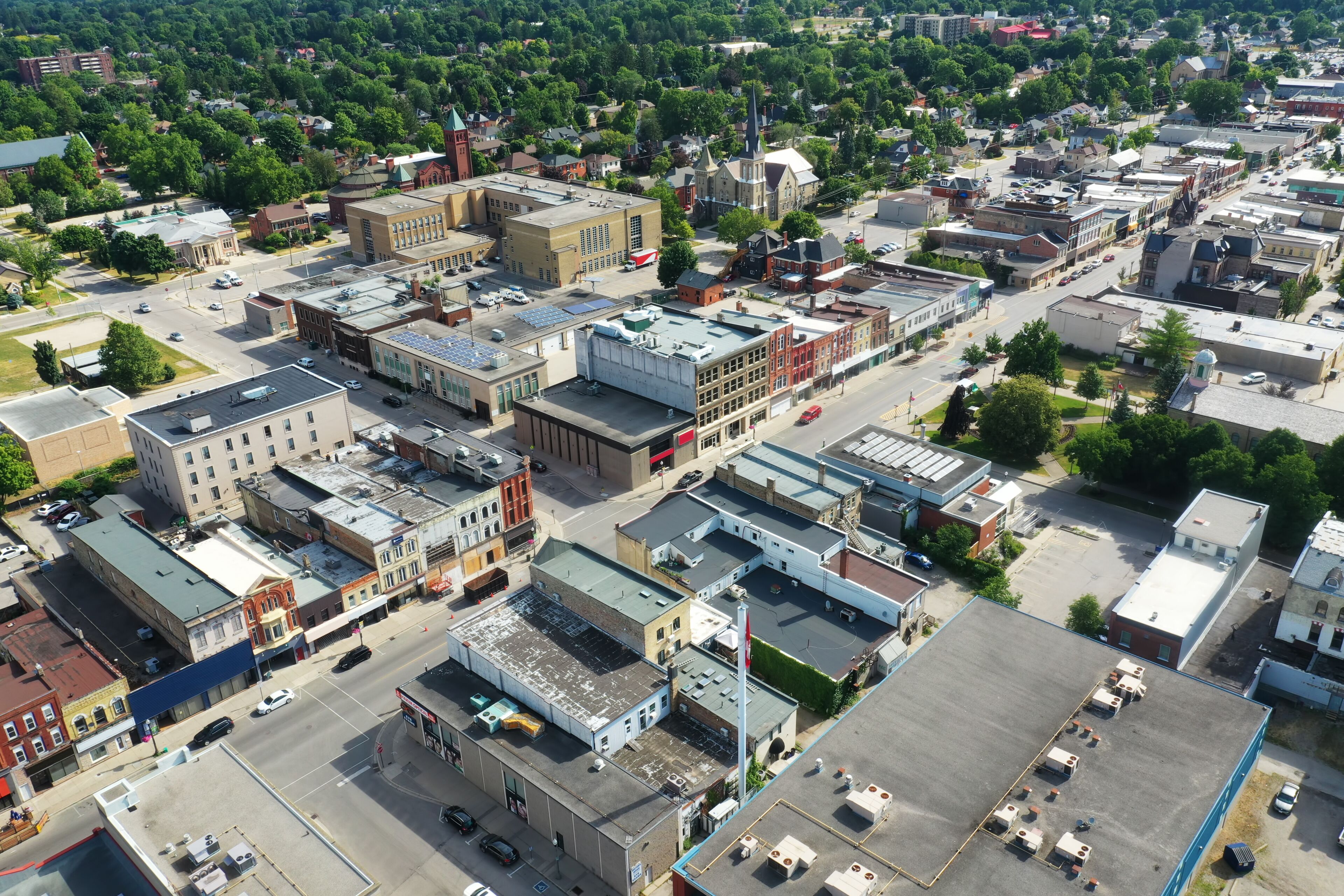 An aerial view of a town with a mix of historic and modern buildings, a prominent church steeple, and a large parking lot.