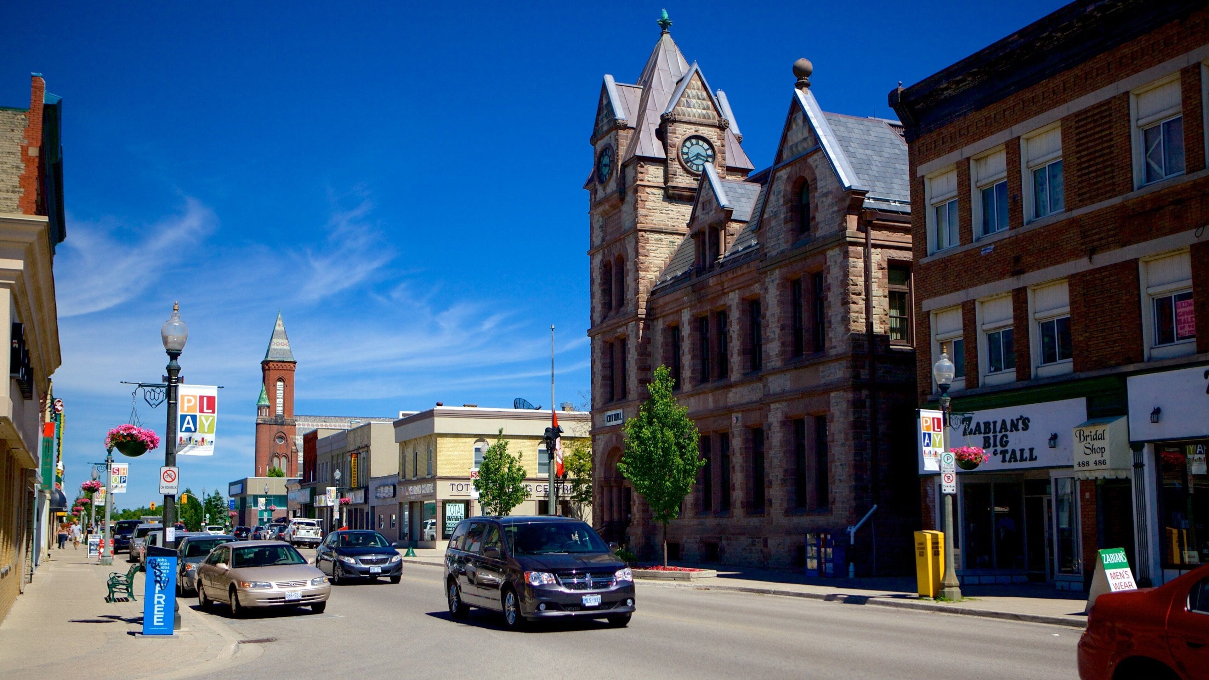 A street with historic buildings, a clock tower, and a bridal shop.