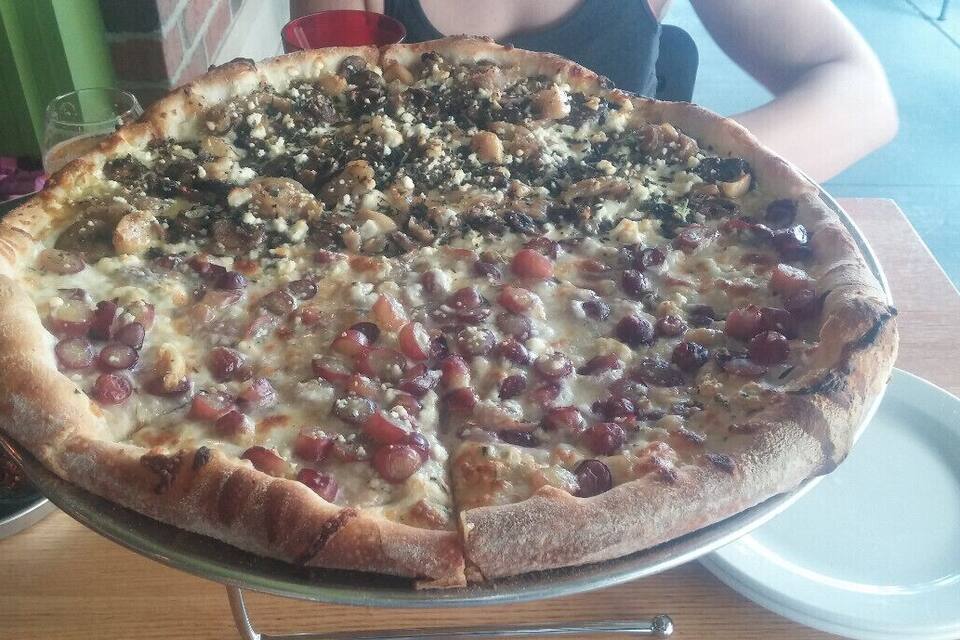 A large pizza with various toppings on a metal tray.