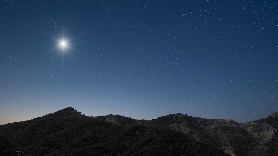 A starry night sky over a mountainous landscape.