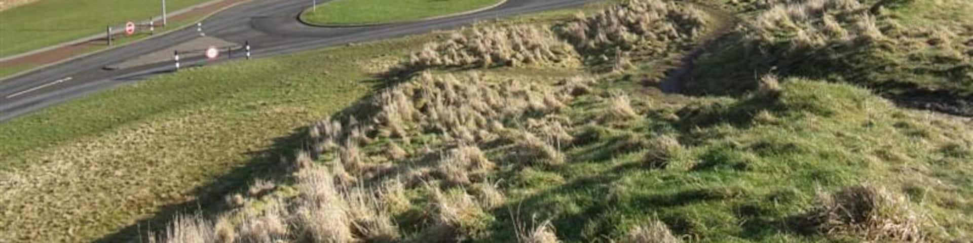 A winding road through a hilly landscape with a mountain in the background.