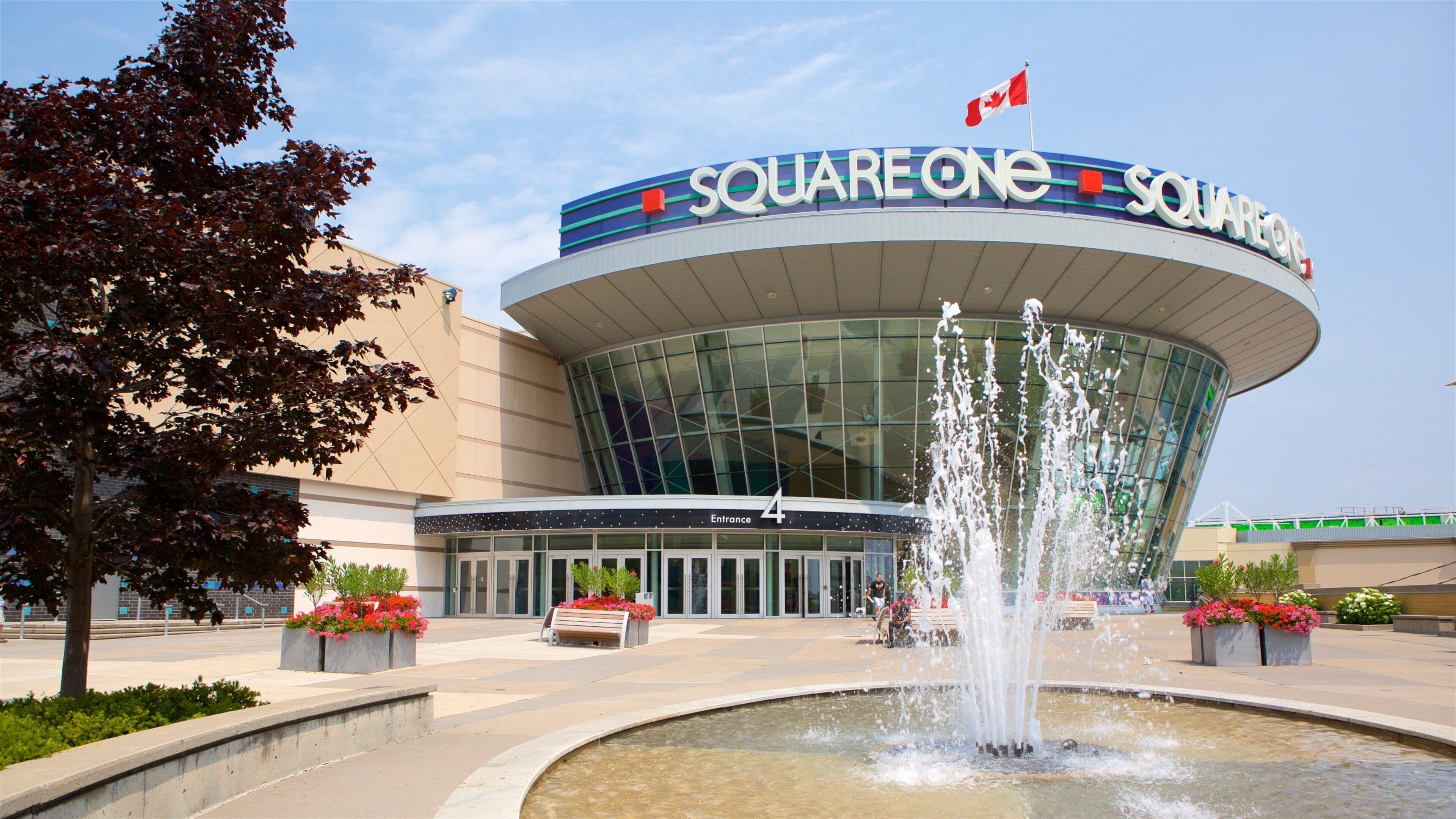 A modern building with a glass facade and a fountain in front.