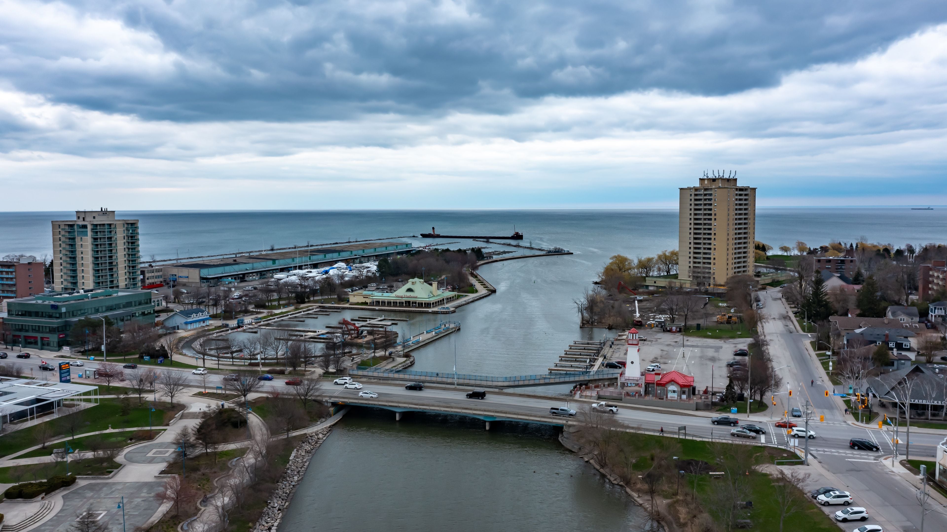 Un paisaje urbano frente al agua, con un puente, un faro y edificios altos.