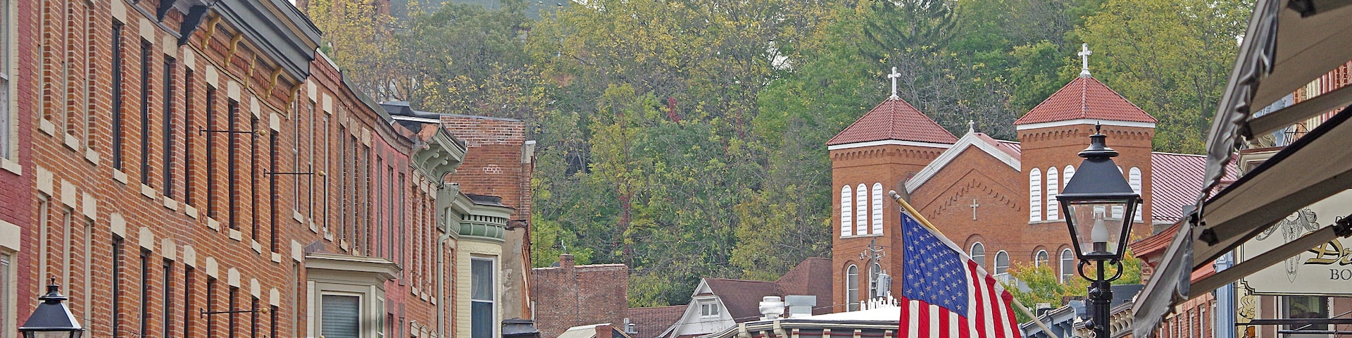 A historic downtown street with American flags, vintage buildings, and a clock tower.
