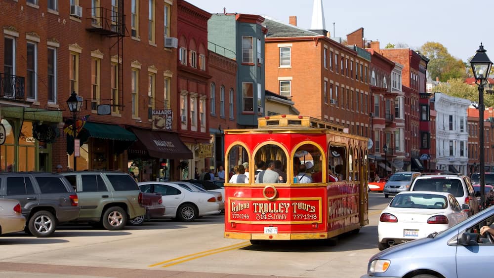 A trolley on a city street with vintage buildings and parked cars.