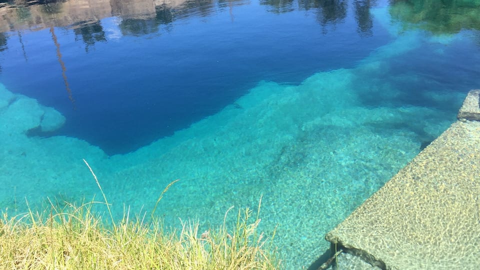 A clear pool with visible underwater rocks and clear water.