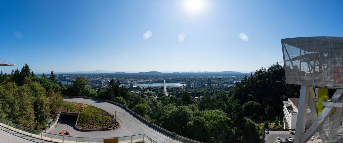 A panorama of the Portland Aerial Tram with the Portland Skyline and Mt. Hood in the background on a clear sunny summer day as viewed from the Oregon Health and Science University.