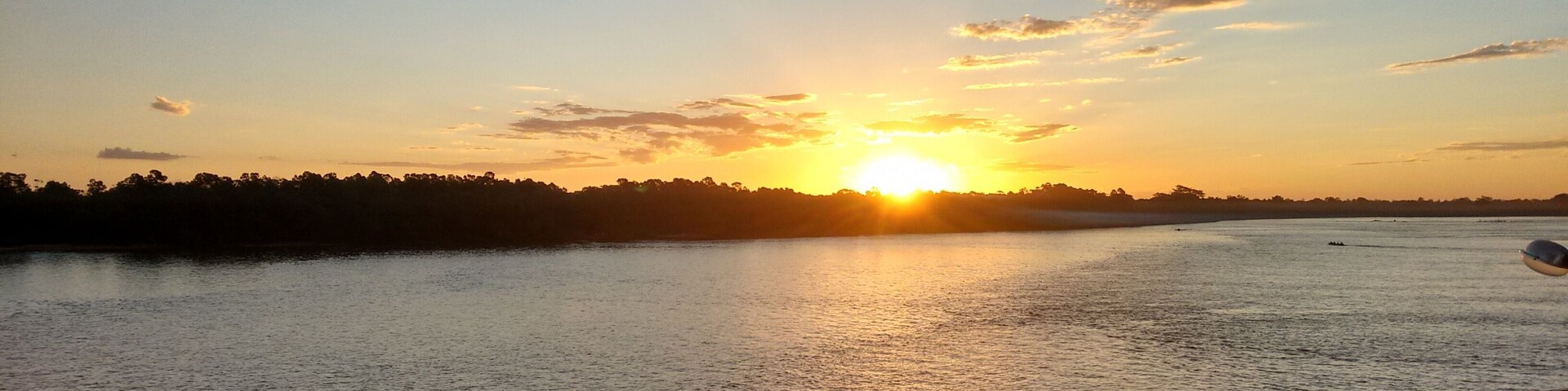 Un atardecer sobre un río tranquilo con una barandilla al frente.
