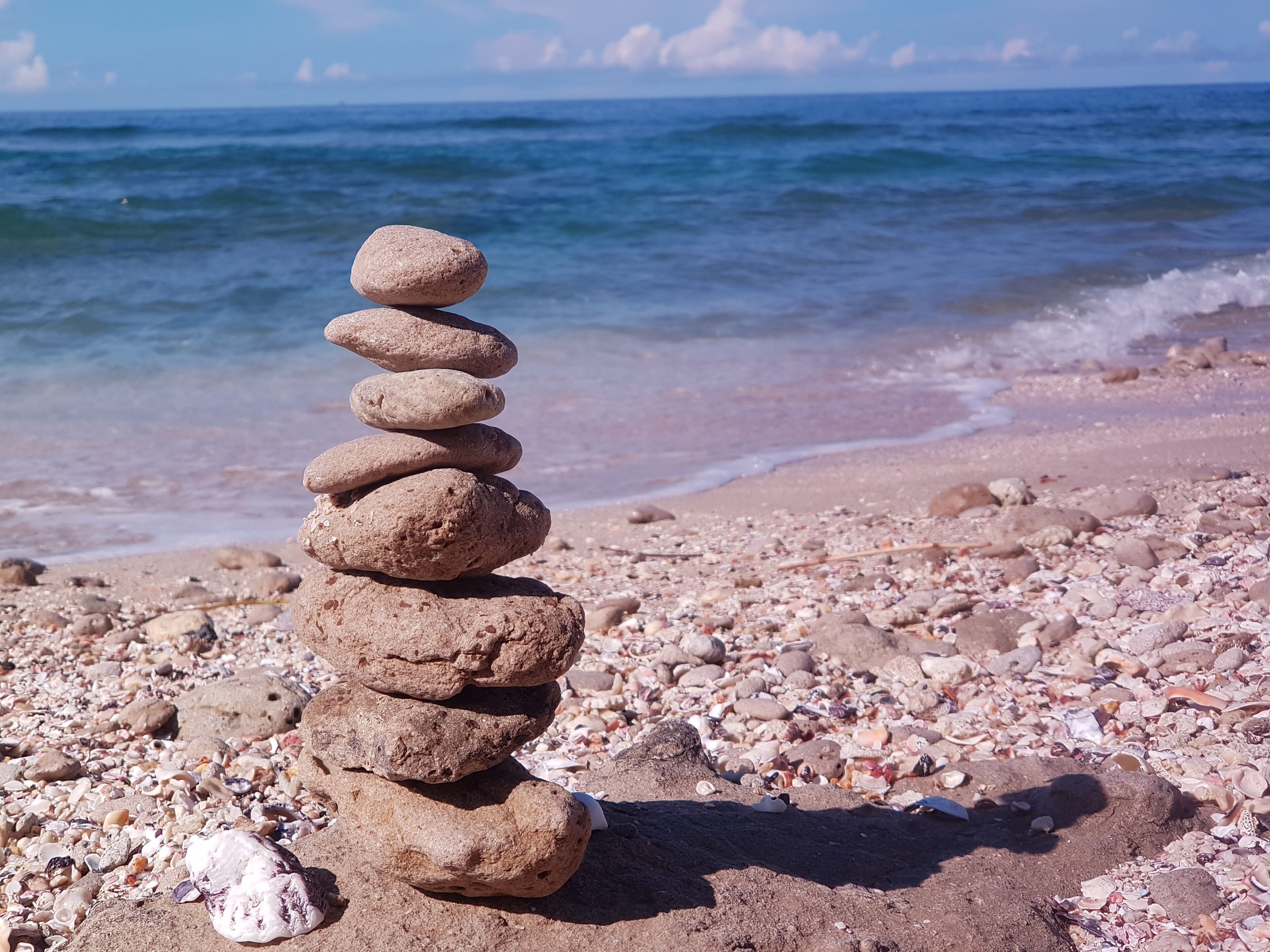 A stack of smooth stones on a pebbly beach with the ocean in the background.