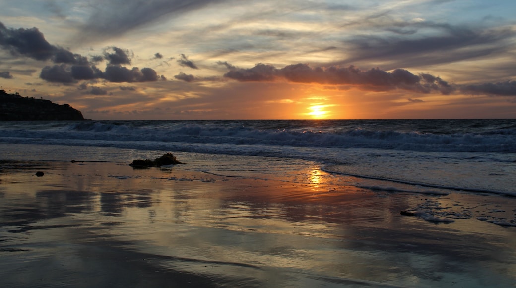 A sunset over the ocean with waves crashing onto the shore.