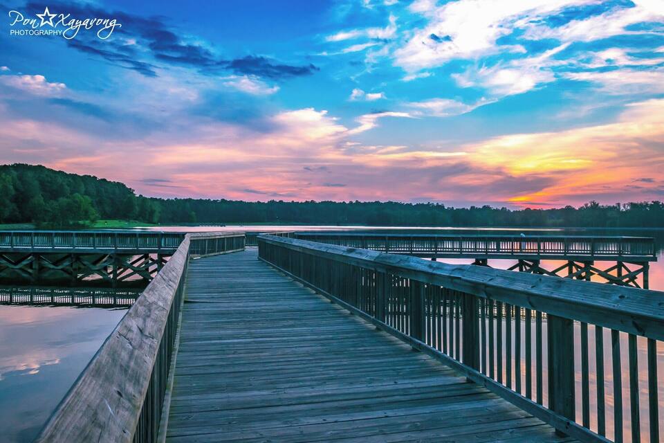 Un muelle de madera que se adentra en el agua bajo un cielo de atardecer.