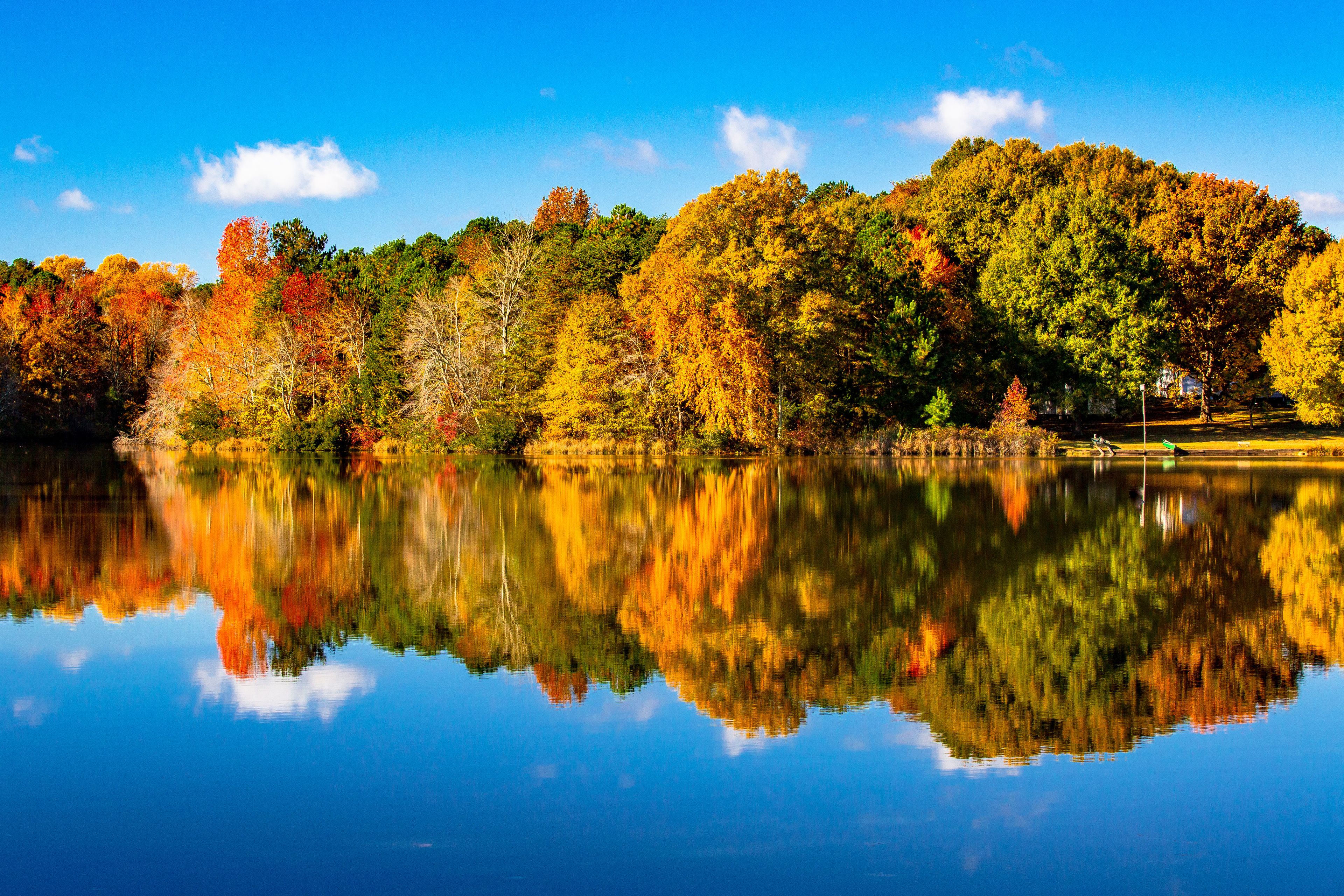 A calm lake reflecting autumn trees with a clear sky.