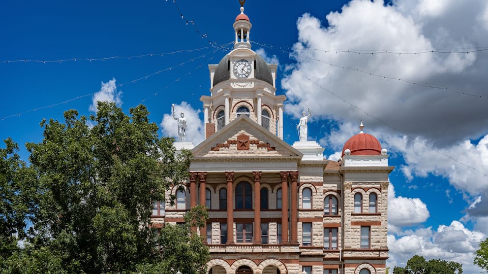 A historic building with a clock tower, arched windows, and statues.