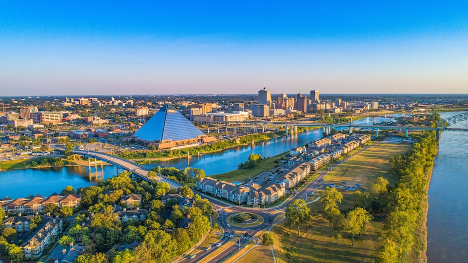 A cityscape with a prominent pyramid-shaped building, a river, and a bridge.