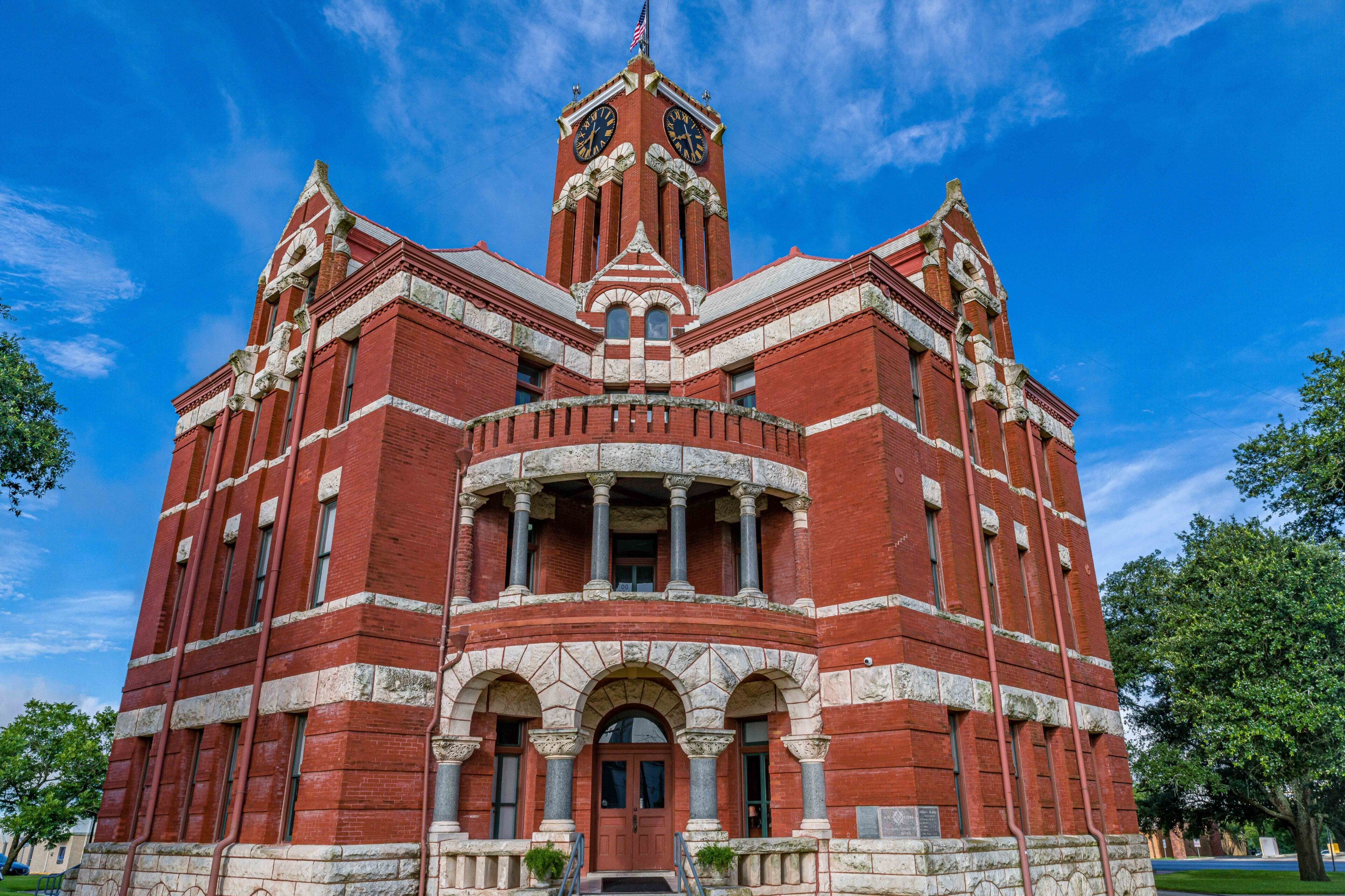 A red brick building with a clock tower, arched windows, and columns.
