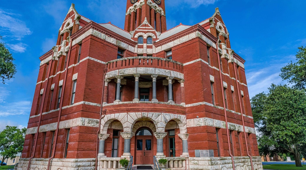 A red brick building with a clock tower, arched windows, and columns.