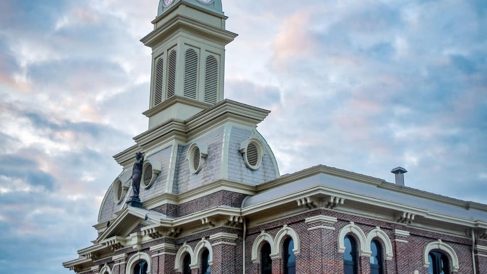 The Scott County Courthouse in Georgetown, Kentucky, with evening traffic passing on Main Street in front of it.