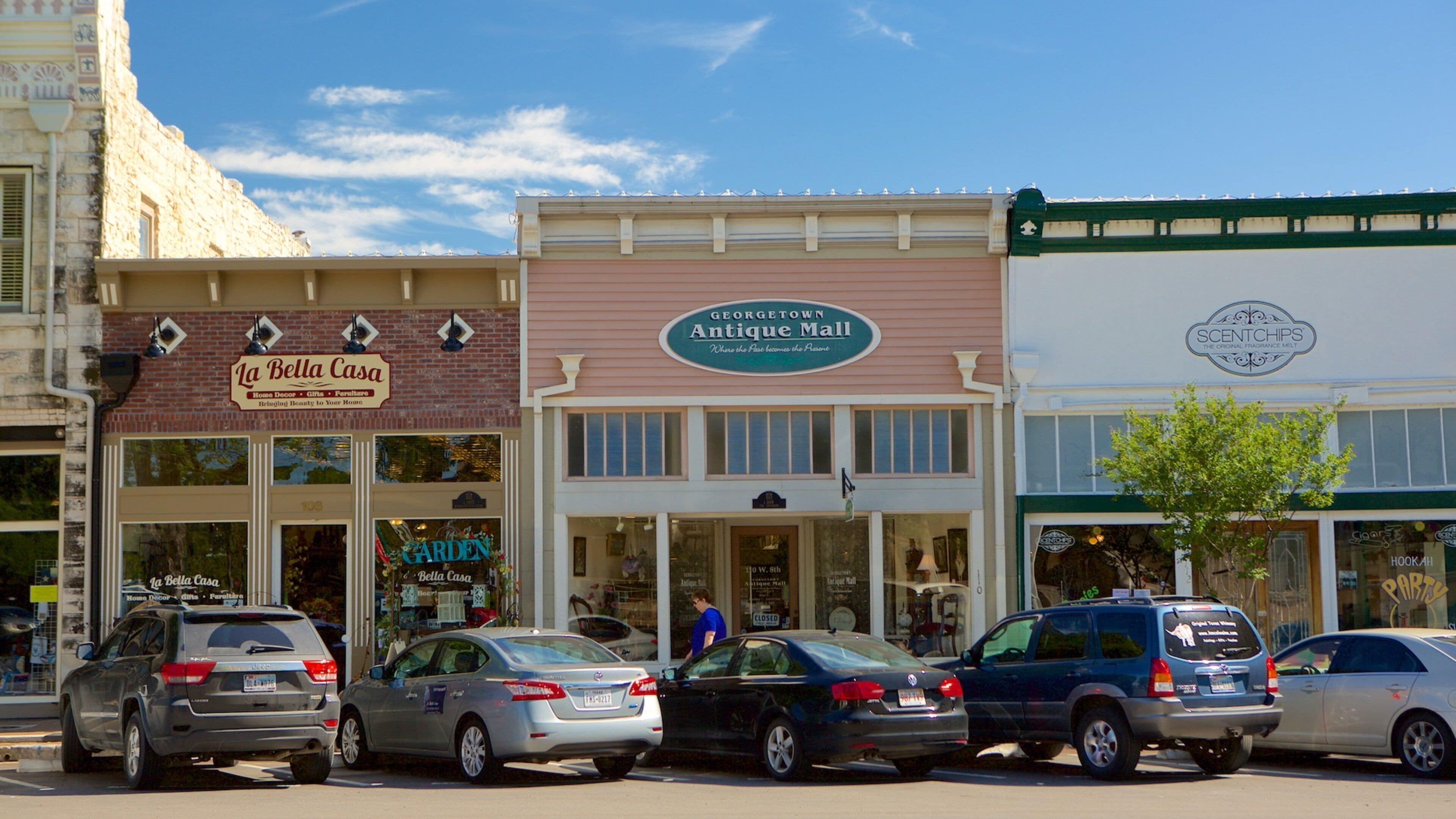 A street with parked cars and storefronts including 'La Bella Casa' and 'Antique Mall'.