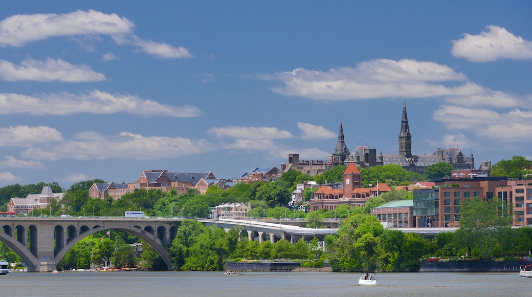 A river with a bridge, a clock tower, and a historic building with spires.